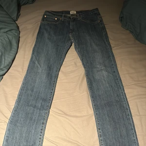 Grant American Classic Jeans 34/32 - Snygga blå jeans från Grant, modell American Classic 405. Regular fit med klassisk femficksdesign och kontrastsömmar. Tillverkade i slitstark denim med rak passform. Perfekta för dig som gillar en tidlös och enkel jeansstil.