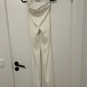 Vita vida byxor med bälte NLY Trend - Snygga vita byxor från NLY Trend i storlek S. Byxorna har hög midja, vida ben och ett matchande bälte med rund spänne. Perfekta för en clean och trendig look. Materialet känns mjukt och har en lätt stretch.