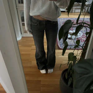 Mörkgrå bootcut jeans låg midja - Säljer ett par mörkgrå jeans med bootcut-modell och låg midja. Jeansen har klassiska fem fickor, snygga slitningar och är tillverkade i ett mjukt denimtyg. Perfekta för dig som gillar en avslappnad och trendig look. Storlek 25W 32L