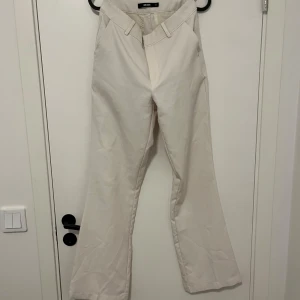 Beiga bootcut byxor från BikBok - Snygga beiga byxor från BikBok i bootcut-modell. Byxorna har hög midja, vida ben och klassiska fickor fram. Perfekta för dig som vill ha en stilren och trendig look. Materialet känns mjukt och bekvämt, troligtvis bomull eller polyester.