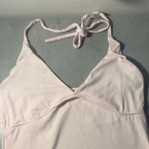 Ljusrosa linnetopp från 157 - Säljer en ljusrosa linnetopp från 157 med smala axelband som knyts i nacken. Toppen har v-ringning och är tillverkad i mjuk bomull, perfekt för varma dagar. Enkel och stilren design som är lätt att matcha.