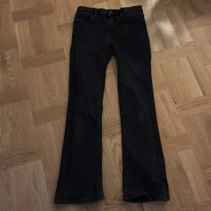 Svarta bootcut jeans från C Denim - Svarta jeans från Cubus Denim i storlek 158. Jeansen har slim bootcut-ben och är lowcwaist med dragkedja och knapp framtill. Jeansen är tillverkade i ett mjukt denimtyg och passar perfekt för dig som gillar en tidlös look.