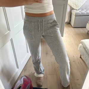 Grå mjukisbyxor Juicy Couture XS - Grå mjukisbyxor från Juicy Couture i storlek XS. Byxorna har snörning i midjan, stora fickor fram och bakfickor med knappdetalj. Mjukt material i bomullsblandning och relaxed passform med raka ben. Perfekta för chill dagar.