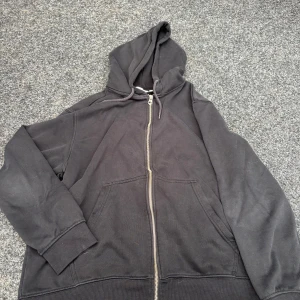 Svart hoodie med dragkedja från Weekday - Svart hoodie från Weekday i storlek M. Klassisk modell med huva, dragsko och hel dragkedja framtill. Mjukt material och två stora fickor framtill. Perfekt för chill dagar eller när du vill ha en enkel streetstyle-look.