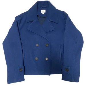 Marinblå kavaj  - Snygg marinblå skepparkavaj från Kappahl i klassisk modell med dubbelknäppning och stora slag. Jackan har raka ärmar med knappar vid ärmslut och är tillverkad i ett mjukt ullmaterial. 