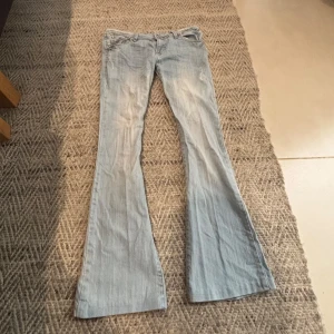 Ljusblå bootcut jeans - Säljer ett par ljusblå jeans med bootcut-modell och klassisk femficksdesign. Jeansen har låg midja och är tillverkade i mjukt denimtyg. Perfekta för dig som vill ha ett par jeans med lite utsvängda ben.