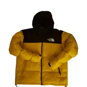 Gul och svart dunjacka från The North Face 700 - Säljer en fet gul och svart dunjacka från The North Face med huva och dragkedja. Jackan har en klassisk pufferstil, stora fickor och logga på bröstet. Perfekt för kalla dagar när du vill hålla stilen och värmen.