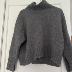 Grå polotröja i kashmir från Soft Goat - Mysig grå polotröja från Soft Goat i kashmir. Tröjan har en hög, ribbad polokrage, långärmade ärmar och ribbade muddar. Oversized passform med något längre bakstycke för en chill look. Perfekt för kalla dagar när du vill vara både varm och snygg.☺️❤️Lite nopprig men går att ta bort❤️☺️