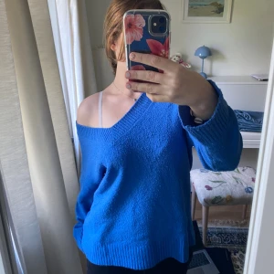Blå stickad v-ringad tröja - Säljer en blå stickad tröja med djup v-ringning och lång ärm från newyorker. Tröjan har en loose passform och kan bäras offshoulder för en chill vibe. Ribbstickade muddar vid ärmslut och nederkant. Perfekt för lager-på-lager under höst och vinter.