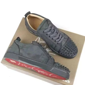 Svarta sneakers från Christian Louboutin - Snygga svarta sneakers från Christian Louboutin med mattsvarta nitar på tån och klassisk röd sula. Skorna har snörning och är gjorda i mocka med en mörk, nästan kamouflage-liknande finish. Perfekta för dig som vill sticka ut med en edgy vibe.skriv för fler bilder dom är fortfarande nya 