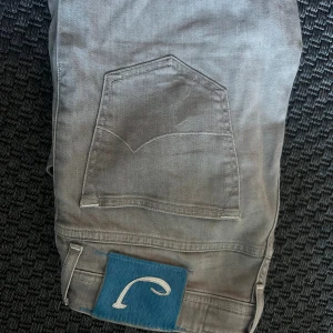  Jacob Cohën jeans stl 31 - Säljer ett par grå jeans från Jacob Cohën i storlek 31. Byxorna har klassisk femficksdesign, raka ben och en snygg blå patch med logga bak. Tillverkade i Italien med exklusiv känsla och detaljerade sömmar. 