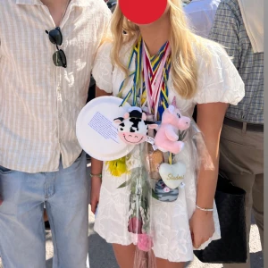 Vit kort klänning med puffärm - Superfin vit kort klänning med v-ringning och puffiga korta ärmar, perfekt till studenten. Klänningen har broderade blommor över hela tyget. Köpt på en dansk hemsida, minns tyvärr inte vad den hette. Använd en gång😊