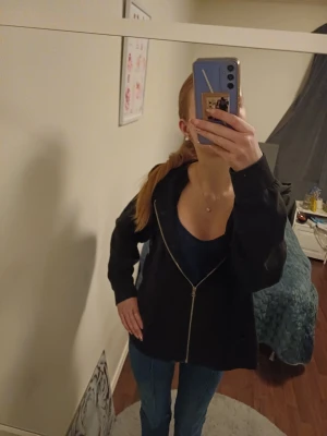 Svart hoodie med dragkedja - Svart hoodie med dragkedja framtill och snörning i huvan. Huddien  har en avslappnad passform och är perfekt för en chill och enkel stil. Tillverkad i mjukt material som känns skönt mot huden. Det är storlek xl men jag har s i vanligaste och den siter perfekt som en overcis huddie 