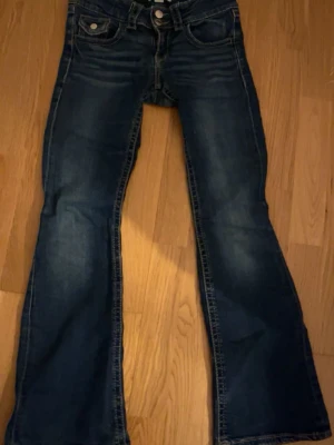 Blå bootcut jeans från Denim - Snygga blå jeans med bootcut passform och klassiska fem fickor. Jeansen har kontrastsömmar och låg midja, vilket ger en cool och avslappnad vibe. Materialet är slitstarkt jeans och färgen har en mörk tvätt med lätt slitning framtill, as snygga men försmå för mig💕