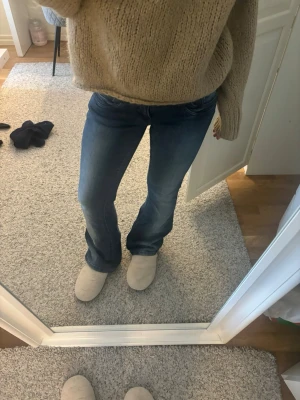 Blå bootcut jeans med normal passform - Säljer ett par snygga blå jeans med bootcut-snitt och normal passform. Jeansen har klassisk femficksdesign, knapp och dragkedja framtill samt lätt tvättad look. Materialet är jeans och midjan är lowaist. Perfekta för dig som gillar en tidlös stil.