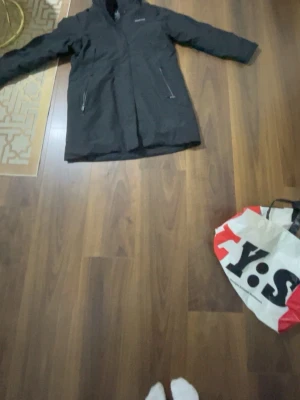 Svart Didriksons parkajacka XL - Svart parkajacka från Didriksons i storlek XL. Jackan har huva, två dragkedjeförsedda fickor och quiltad insida. Perfekt för kalla dagar med sin långa modell och stilrena look. Materialet är polyester och jackan har en snygg, enkel design.Den är inte använd men har ingen prislapp Elle orginalförmacking