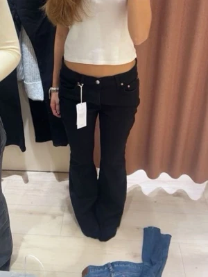 Svarta bootcut jeans med låg midja - Snygga svarta jeans med bootcut-snitt och låg midja. Klassisk femficksmodell med knapp och dragkedja fram. Jeansen har en stilren look och är tillverkade i ett mjukt jeansmaterial som sitter skönt. Perfekta för dig som gillar en tidlös och cool stil.