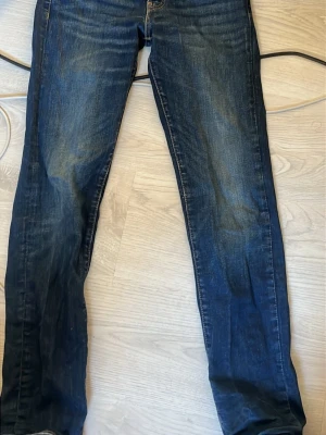 Levi's 511 mörkblå jeans W28 L32 - Säljer ett par Levi's 511 jeans i mörkblå tvätt med klassisk femficksdesign och snygga slitningar. Modellen är slim fit med smal passform och raka ben. Jeansen har detaljer som bruna sömmar och läderpatch bak i midjan. Perfekta för dig som gillar stilrena och tidlösa jeans.