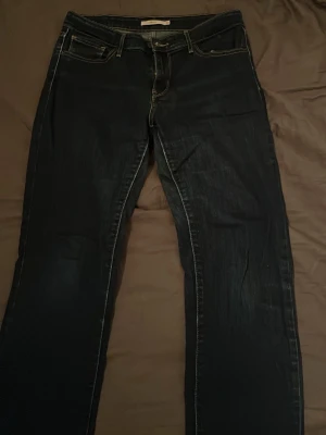 Levi's 712 Slim jeans mörkblå W30 L32 - Säljer ett par Levi's 712 Slim jeans i mörkblå tvätt med klassiska kontrastsömmar och fem fickor. Modellen har slim passform och normal midja. Materialet är slitstarkt jeans och bakfickan har den ikoniska Levi's etiketten.