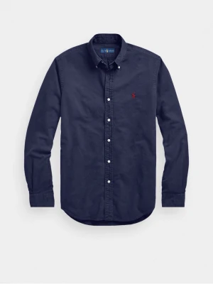 Mörkblå skjorta från Ralph Lauren - Klassisk mörkblå skjorta från Ralph Lauren med knappslå och vit knappstängning. Skjortan har lång ärm och ikonisk röd broderad logga på bröstet. Tillverkad i mjuk bomull för en bekväm känsla och snygg passform.