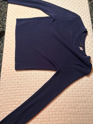 Mörkblå stickad tröja från H&M Divided - Säljer en mörkblå stickad tröja från H&M Divided i storlek XS. Tröjan har långärmade, ribbade detaljer och en klassisk rund halsringning. Perfekt för dig som gillar enkel och stilren design med en skön passform.