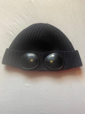 Svart mössa  från C.P. Company - Säljer en svart ribbstickad mössa från C.P.Company . Det är den äldre modellen därför har den inte texten på ena glaset. Bara höra av sig om nu undrar något. Pris kan diskuteras.