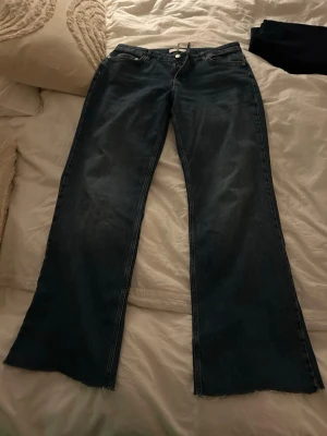 Wide jeans från NA-KD i mörkblå denim - Säljer ett par mörkblå jeans från NA-KD med breda ben och låg midja. Avklippta nertill passar mig som är 165 cm lång och då går de över skorna.