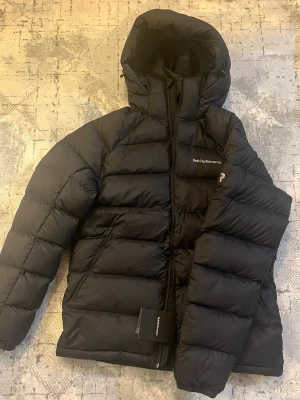 Svart dunjacka Peak Performance  - Jackan är inte använd någon gång på grund av att den inte passar lika bra. Köpte den för 2800 kr men väljer att sälja den för 2100 kr på grund av att den tyvärr blivit hängande i garderoben sen 25-9-30 som ni ser på kvittot.