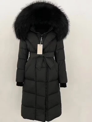 Svart lång dunjacka med päls - Säljer en svart lång dunjacka med stor fluffig päls på huvan och bälte i midjan. Jackan har quiltad design, dragkedja framtill och långa ärmar. Perfekt för kalla dagar när du vill vara både varm och snygg.