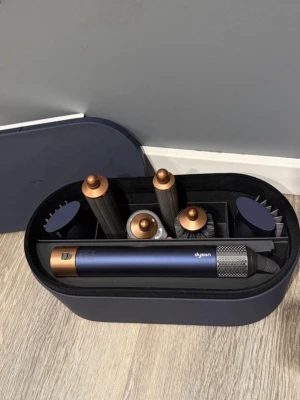 Dyson airwrap med kvitto !!!!! - Snyggt set med Dyson stylingverktyg i mörkblå och kopparfärg. Inkluderar flera olika borstar och stylinghuvuden i plast och metall, allt i en matchande mörkblå förvaringsbox. Perfekt för att fixa håret med olika looks och volym.