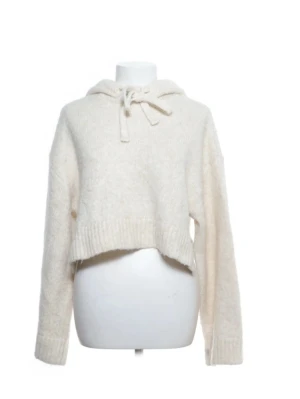 Beige croppad stickad hoodie från Zara - På bilden är snörena  knuten. Mysig croppad hoodie från Zara i beige stickat material. Tröjan har huva med snörning och långa ärmar. Perfekt för dig som gillar en avslappnad och trendig stil. Ribbstickade muddar vid ärmslut och nederkant ger extra komfort.