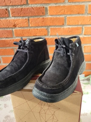 Svarta mockakängor från JPW, fodrade, EUR 37 - Säljer ett par svarta kängor från JPW med mjukt foder och grov platt sula. Skorna har snörning framtill och är tillverkade i mocka, vilket ger dem en schysst och stilren look. Perfekta för dig som gillar klassisk stil med lite edge.