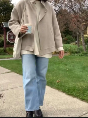 Beige kort kappa från Mango, L - Kort beige ull kappa från Mango i en loose passform. Jackan har snygga knappar framtill, bred krage och stora fickor på sidorna. Materialmix av ull och polyester ger en mjuk och stilren känsla. Perfekt för lager-på-lager och chill höststil.