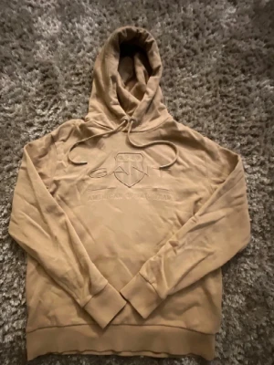 Beige hoodie från GANT  - En ljus brun hoodie från GANT i storlek L men den sitter som S/M, den är i ett otroligt bra skick och inga skador. Den är perfekt för dig som gillar det enkla. Har du några frågor så är det bara o skriva.