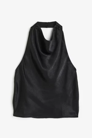 Svart halterneck topp i satin - Säljer en svart halterneck topp i glansigt satinmaterial. Toppen har öppen rygg och knäpps i nacken med knapp. 