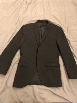 Svart kavaj från Tiger of Sweden - Snygg svart kavaj från Tiger of Sweden, tillverkad i sammarbete Angelico. Klassisk design med smal passform. Använd 1 gång tidigare. Köpte den för 3500:-. Kan sänka priset vid snabb affär.