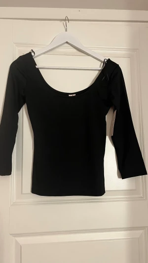 Svart långärmad topp med rund hals - Säljer en stilren svart topp med rundad halsringning och lång ärm. Toppen har en tight passform och är tillverkad i ett mjukt och stretchigt material, perfekt att matcha med jeans eller kjol. Enkel och snygg design som funkar till många olika looks.