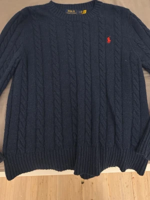 Marinblå stickad tröja Polo Ralph Lauren - Säljer en marinblå kabelstickad tröja från Polo Ralph Lauren i storlek S. Perfekt för dig som gillar klassisk och stilren design. Passar XS oxå!! Tags finns.