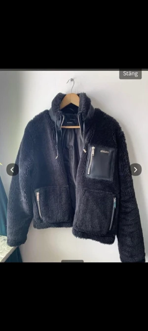  Axel Arigato svart teddy jacka - Svart teddyjacka från Axel Arigato med coola detaljer i skinn på bröstet och axeln. Jackan har dragkedjor på fickorna och hög krage med snörning. Perfekt för dig som gillar streetwear och vill ha något som sticker ut knappt använd nyskick säljes pga blivit för liten för mig..priset kan diskuteras vid en smidig affär jackan fins i Fagersta för upphämtning vid intresse eller frakt med posten..MVh t