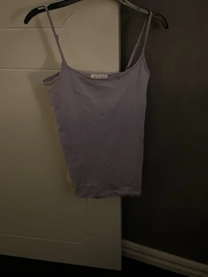 Ljuslila linnetopp  - Säljer en ljuslila linnetopp från Amisu med smala axelband och enkel, rak passform. Toppen är ärmlös och har en mjuk känsla, perfekt att styla med jeans eller kjol. Färgen är fräsch och passar till många olika looks.