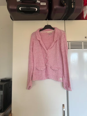 Rosa stickad kofta Odd Molly - Säljer en rosa stickad kofta från Odd Molly med snygg krage och dekorativa knappar framtill. Koftan har två små fickor med lock och ett unikt mönster i stickningen. Perfekt för dig som gillar mjuka och mysiga plagg med lite extra detaljer. Storlek 1 som enligt deras storleksguide motsvarar en S.  mer använd men fortfarande fin. Midjeband saknas. 