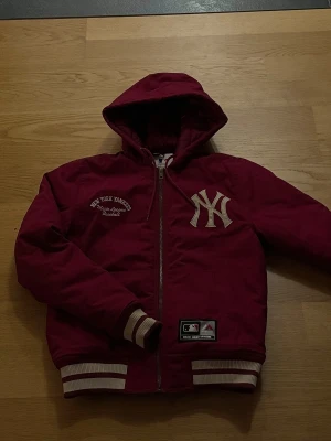New York Yankees jacka Majestic Athletics - Helt oanvänd röd Majestic Athletic jacka i fint skick. Broderade loggor, ribbade muddar, samt quiltat foder. Storlek small.