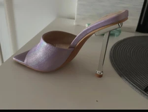 Lila glittriga klackskor från Shein Helt ny! - Säljer ett par lila glittriga klackskor med öppen tå och spetsig framdel. Skorna har en unik metallklack med hög klackhöjd och en fyrkantig sula. Materialet är syntet med skimrande finish som ger extra wow-effekt. Perfekt för dig som gillar att sticka ut.
