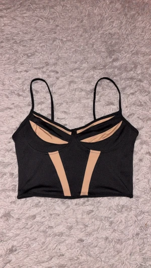 Svart och beige korsettinspirerad topp - Säljer en svart korsettinspirerad topp med beige detaljer och tunna axelband. en fin kort tank top från shein. kom aldrig till användning.   mer bilder? kontakta mig