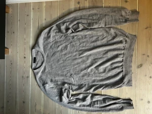 Grå stickad tröja från Stenströms - Snygg grå merinoull stickad tröja från Stenströms med rund halsringning och ribbade muddar vid ärmslut och nederkant. Perfekt för lager-på-lager och funkar året runt. Enkel och stilren design som passar till det mesta. Skick: 10/10. Nypris: 2599kr