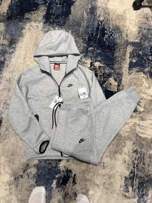 Nike tech fleece grå - Helt ny Nike tech i storlek M. Han på bild är 185 cm, 75kg. Tracksuiten är helt ny. Hör av er vid funderingar!