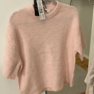 Stickad ljusrosa topp XS - Superfin stickad topp i ljusrosa med korta ärmar och rund hals. Mjuk och mysig känsla, perfekt för dig som gillar en enkel men söt look. Ribbstickade kanter vid ärmslut och nederkant. Säljes då den inte kommer till användning!