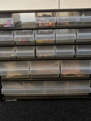 Förvaringsskåp med berlocker  - Förvaring med 18 lådor. I lådorna ligger berlocker och andra saker man behöver för att själv kunna tillverka smycken. Säljer då jag hade en egne small business för nått år sen men använder inte de längre. Perfekt nu till julklapp.