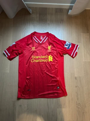 Liverpool tröja - Bilderna visar en röd Liverpool FC matchtröja med Suarez och nummer 7 på ryggen, samt Premier League-märke på ärmen.