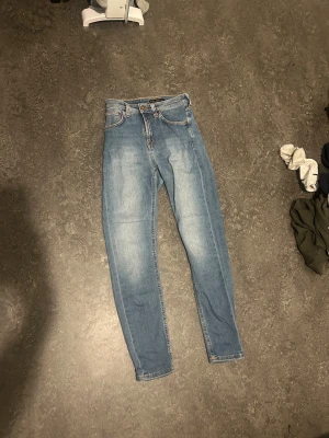 Blå  Nudie Jeans - Säljer ett par ljusblå slim jeans från Nudie Jeans med klassiska orange sömmar och fem fickor. Jeansen har slim passform och är tillverkade i mjukt denimtyg. Perfekt för dig som gillar nudie jeans 